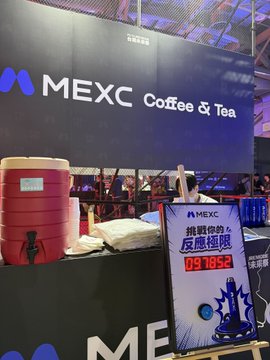 A MEXC Coffee & Tea booth at a crowded event features a large red beverage dispenser, coffee equipment, and a sign reading “挑戰你的 交易極限” with “09 105s.”