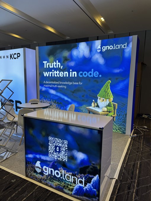 An event booth displays signage for "gno.land" with the slogan "Truth, written in code." and a pixel-art gnome mascot.
