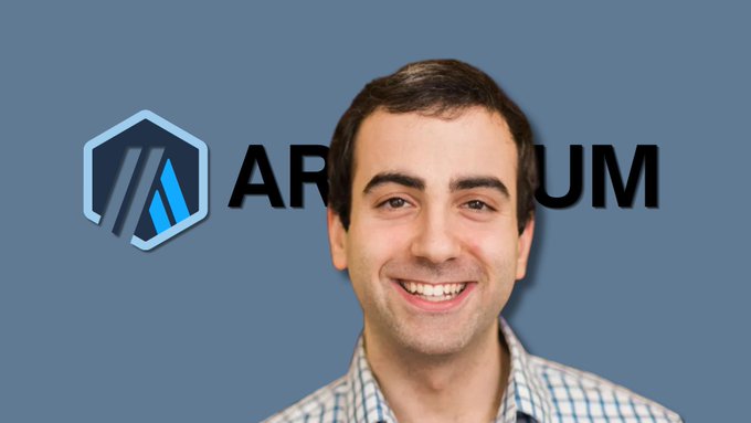 The image features a man with a big smile, wearing a plaid shirt, standing against a blue background that prominently displays the word "ARTMUM" above him. The text "in crypto airdrop history, no project gonna distribute rewards like arbitrum did, with minimum effort, all you had to do was: bridge assets to arbitrum > do 2-3 transactions per month ... and receives $2k to 5 figures at the approximately 600k+ wallets wereeligible" is written above him. This text seems to be related to a post about cryptocurrency or an event involving cryptocurrency.