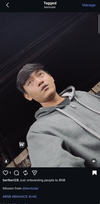 A young man in a gray hoodie looks up at the camera in a close-up selfie-style shot with a dark ceiling above him. The Instagram post by "berlberl28" references the video, mentioning "Just onboarding people to BNB" with a mission from @bentodar, tagged with #BNB #BINANCE #UAE.