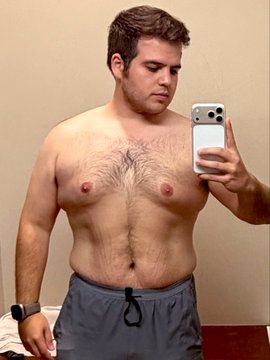 The image shows a man taking a selfie with his cell phone, capturing himself in front of a mirror. The man appears to be wearing shorts and has a muscular torso. He seems to be in a bathroom setting, as there are two sinks visible in the background. The photo is titled "Bull Run" which suggests that this might be related to an event or challenge involving weight loss or fitness goals.
