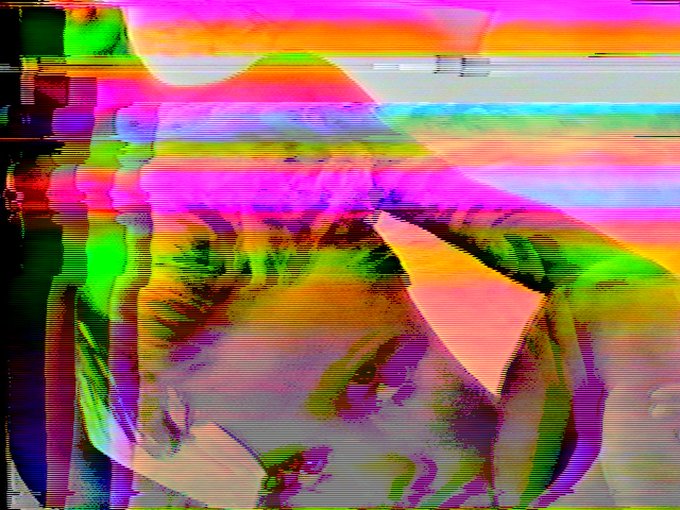 A heavily glitched, distorted image with vibrant pink, green, and orange colors and visible scan lines, appearing to show an abstract figure.