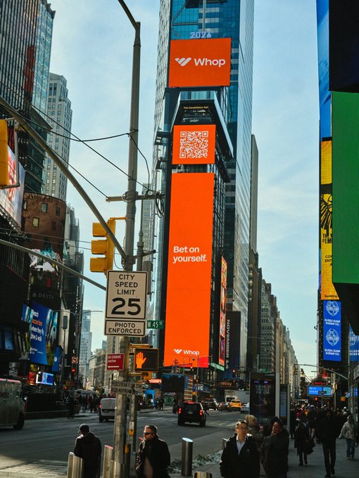 A towering orange Whop advertisement with the slogan "Bet on yourself" and a QR code dominates a Times Square skyscraper, framed by a "City Speed Limit 25 / Photo Enforced" sign and bustling pedestrians below. The scene captures the kind of bold, high-visibility marketing takeover the post predicts will define 2026, following crypto Twitter's 2024 playbook.