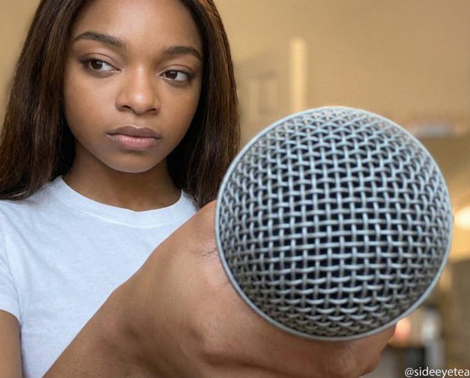 A young woman looks skeptically at a microphone being held toward her; the image is credited to '@sideeyetea' in the corner.