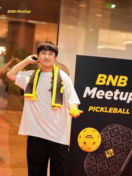 A young man poses with a pickleball paddle over his shoulder and ball in hand at a "BNB Meetup Pickleball" event, likely participating in the BNB-organized coaching session mentioned in the post about finally learning the sport that had been popular during his studies in Malaysia.