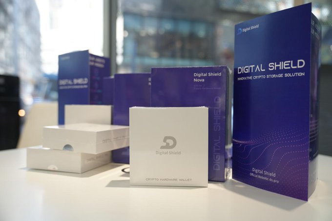 Product photography of 'Digital Shield' crypto hardware wallets and packaging arranged on a white surface, including the 'Nova' edition in a blue box and a white device labeled 'Crypt Hardware Wallet', marketed as an 'Innovative Crypto Storage Solution'.