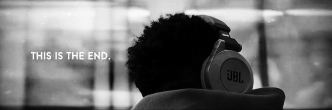 The image features a person wearing headphones, possibly an Apple or JBL brand, while sitting down. The background of the photo has a window that allows light to enter the room. There are also some words written above the person's head, which seem to be part of a caption or message related to the image.