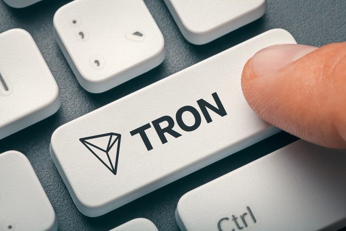 A close-up photo shows a finger pressing a white computer keyboard key labeled "TRON" with the TRX diamond logo, positioned next to the Ctrl key.