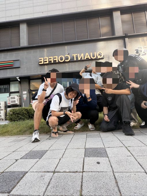 A group of young people posing playfully on a sidewalk in front of a building with "QUANT COFFEE" written on the window (appearing mirrored), with most faces blurred for privacy.