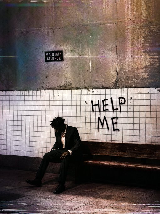 A distressed man in a dark suit sits slumped on a bench in a grimy tiled subway-like space beneath graffiti reading “HELP ME”; a small wall sign says “MAINTAIN SILENCE.”