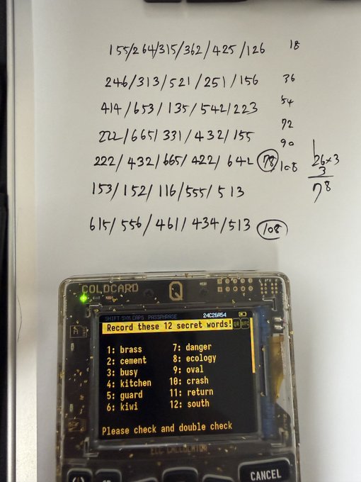 The image shows a Coldcard hardware wallet displaying a 12-word BIP39 seed phrase backup screen alongside handwritten paper notes containing number sequences and calculations used to generate the seeds, illustrating how users were creating low-entropy wallets from manual entropy—a practice that led to widespread compromise of funds.
