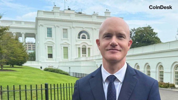A bald man in a navy blue suit stands outside the White House, with the "CoinDesk" watermark visible in the upper right corner. The image relates to the post's discussion of Coinbase CEO Brian Armstrong's interview about crypto legislation and regulatory clarity in Washington.