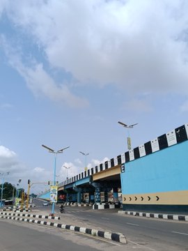 A street view captures a road with a flyover featuring black and white striped barriers and blue underpass walls, under a partly cloudy sky. The image shows no visible text or numbers, but accompanies a "GM CT" post where the user is sharing the photo they took, describing it as "dope."