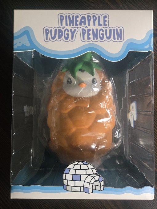 A collectible figure called 'PINEAPPLE PUDGY PENGUIN' in its original packaging, showing an orange penguin with a pineapple-like textured body and green leafy top.