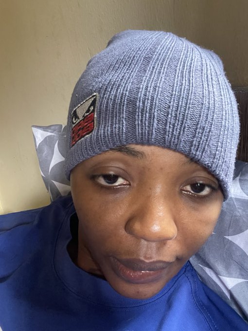 Selfie of a person wearing a gray knit beanie with an 'EAGLES' patch and a blue shirt, sitting against a pillow.