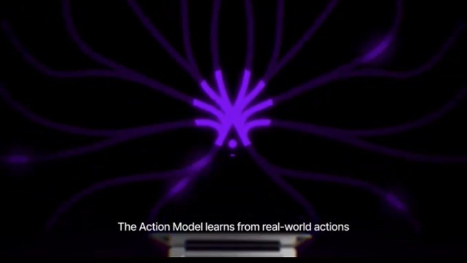 The image features a purple flower with eight petals arranged in a circular pattern against a black background. The text at the bottom of the image reads "The Action Model learns from real-world actions", indicating that the model is designed to learn from actual world events and behaviors, rather than just speculation or hype.