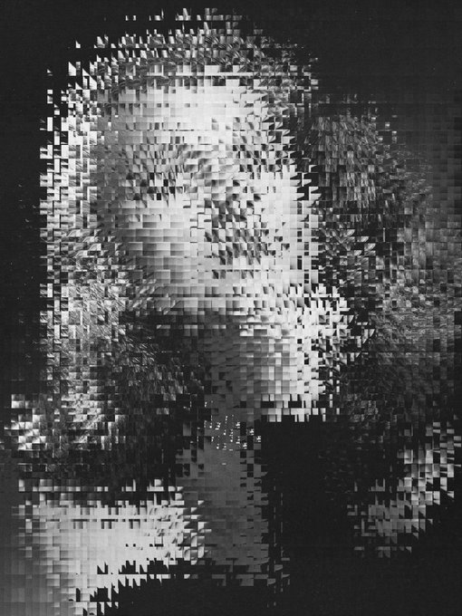 A high-contrast, pixelated or fragmented black-and-white portrait of a face, appearing as if made up of many small rectangular pieces.