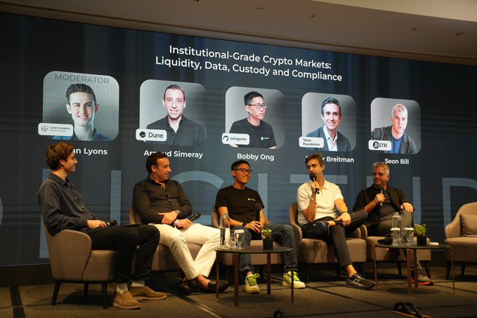 A panel of five men sits on stage discussing "Institutional-Grade Crypto Markets: Liquidity, Data, Custody and Compliance," with the screen behind them displaying their names and companies: Moderator Ciaran Lyons, Arnaud Simeray (Dune), Bobby Ong (coingecko), Arthur Breitman (Tezos Foundation), and Soon Bill (BSTR).