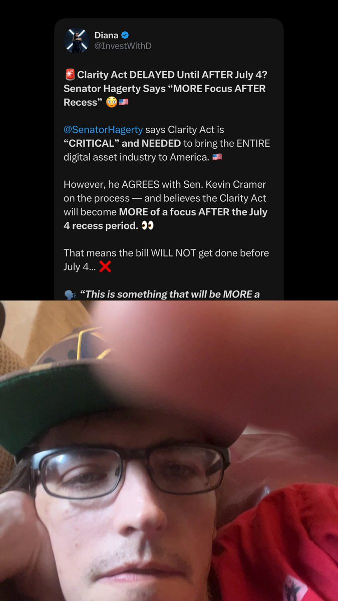 The image shows a man wearing glasses, with his head resting against a wall or a pillow. He has a red shirt on and appears to be taking a break from work by leaning back into a chair. The background of the image is dark, which makes him stand out more prominently in the photo. There are also some text elements present in the image that seem to be related to the post about the delayed release of an album or a movie.