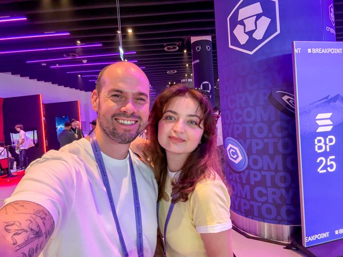 Two people smiling for a selfie at a crypto event, with 'CRYPTO.COM' branding and 'BP 25' signage visible.
