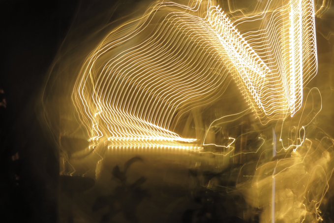 Abstract golden light trails form swirling, ribbon-like patterns created by long-exposure photography of moving lights.