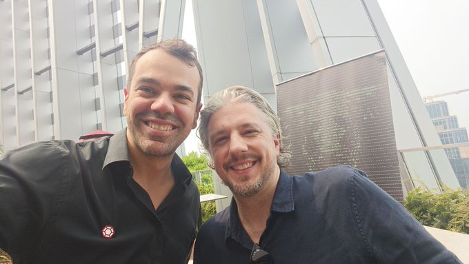 Two men smile for a selfie outside a modern glass building, accompanying a post announcing their arrival in Singapore—identifying the dark-haired man on the left as Mike Massari (Head of Partnerships at Redstone DeFi) and the gray-haired man on the right as Jeff Marsilio (Head of Commercial at Newton Labs).