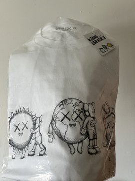 A packaged white long-sleeve shirt from the brand 'otmxxz' featuring black line-art prints of small creature characters alongside KAWS-style 'XX' figures.
