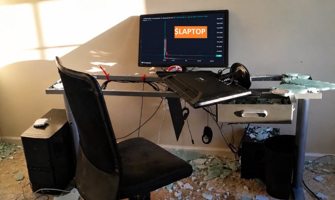 A destroyed computer setup in a debris-filled room, featuring a desk with a monitor displaying '$LAPTOP' on a trading chart, a gaming chair, a desktop tower, and shattered glass scattered across the floor.