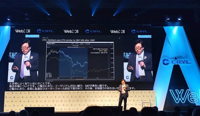 A man in a suit gives a presentation on stage at a WebX/CRYL event, with large screens displaying a chart titled 'ETH: DeMark sees ETH similar to S&P 500 after 1987' showing XETUSD Current chart data, alongside Japanese subtitles and logos for WebX and CRYL.