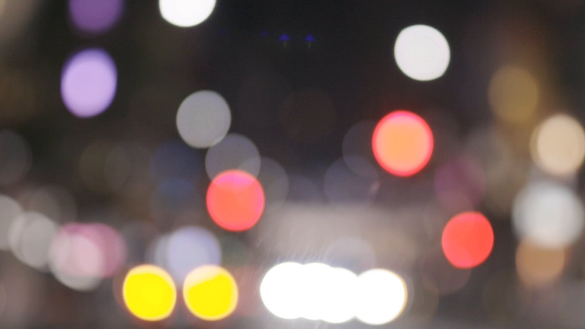 The image shows a city street at night with bright lights from cars, buildings, and other sources of illumination. There are several circles of light scattered throughout the scene, creating a visually striking effect. In the background, there's a sign that reads "Avalanche Gourmet Night Tokyo", indicating that this is an event or gathering related to gourmet food in Japan. The image also contains text elements such as "@avalanchejp" and "@wrathtank_avax".