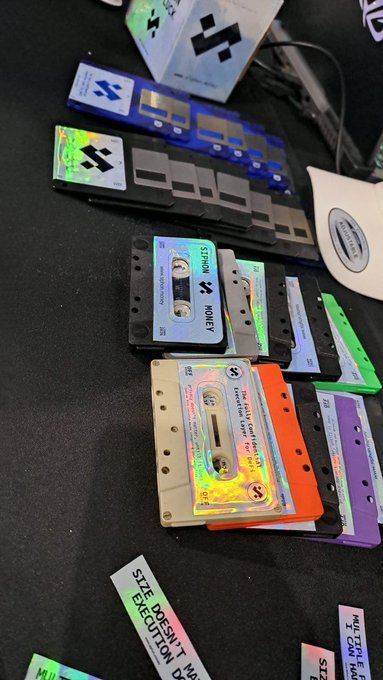 A collection of colorful mixtape cassette tapes and cards scattered on a dark surface, with visible titles like '$5300NL', 'MONEY', and a card reading 'SEE DOESN'T EXECUTION'.