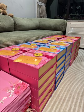 Numerous colorful gift boxes with smiley face designs stacked neatly on the floor in front of a green sofa.