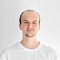 Image 9: A simple ID-style portrait of a smiling young man with short blonde hair and light facial hair, wearing a plain white crew-neck t-shirt against a solid light grey background.
