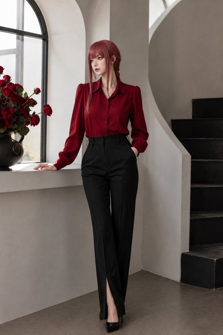 A young woman with long red hair wearing a burgundy blouse and black pants stands in an elegant interior with an arched window, red roses in a vase, and a curved staircase.