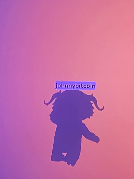 A purple silhouette of a horned character with the username 'johnnybitcoin' displayed on a pink and purple gradient background.