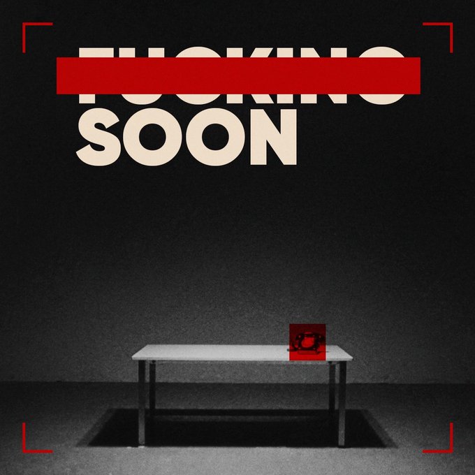 A dark, moody image featuring the text "FUCKING SOON" in large, bold, beige letters against a black background, with a red bar partially crossing through "FUCKING". Below, a small table holds a red square object in a room with a shadowy ambiance.