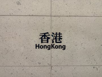 A stone tile wall engraved with "香港 Hong Kong," indicating the event took place in Hong Kong, likely near a high-speed rail station as referenced in the post about attending the Binance VIP private gathering.