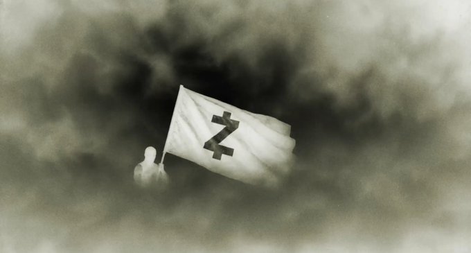 The image features a stylized flag emblazoned with the Zcash symbol (a "Z" with two horizontal stripes through it), which relates to the post's mention of ZEC (Zcash cryptocurrency) as the token used in the NFT auction.

**Caption:** A mysterious figure holds aloft the Zcash "Z" flag against a smoky, atmospheric backdrop, evoking the elusive and revelatory tone of the post's announcement about the launch of "Zilkroad," a trading platform for zkSNARKs NFTs purchased with ZEC.