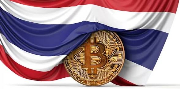 The image shows a physical Bitcoin coin displayed against the backdrop of the Thai national flag. This visual ties directly to the news that Thailand has approved Bitcoin ETFs for trading on its domestic stock exchange, beginning October 16.