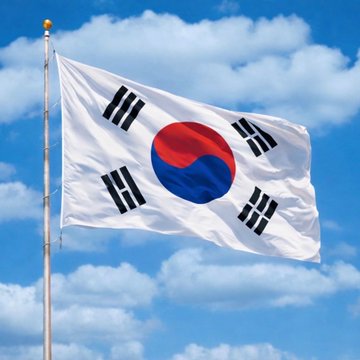 The South Korean national flag (Taegukgi) waving against a blue sky filled with white clouds.