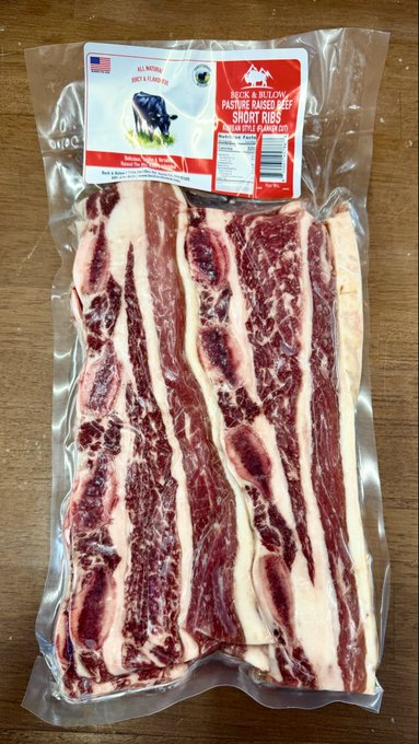 A vacuum-sealed package of Back & Bullion Pasture Raised Short Ribs with a USDA label rests on a wooden surface, matching the advertised offering.