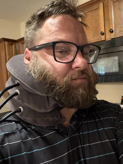 A bearded man wearing black-framed glasses and a striped shirt sits in a kitchen while wearing a cervical neck traction device, humorously visualized as "adding liquidity" to his neck to raise its "TVL" (Total Value Locked) alongside his stock portfolio recovery efforts.
