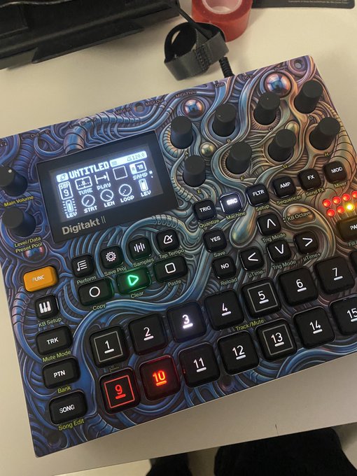 An Elektron Digitakt II drum machine and sampler with a colorful blue and purple psychedelic pattern, featuring a small display showing 'UNTITLED', an SD card inserted, and various knobs and buttons including a green play button and red-lit number pads.