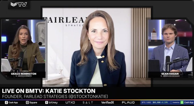 A BMTV live broadcast features a three-way split screen with Grace Remington and Sean Hagan hosting from their studio, while Katie Stockton, Founder of Fairlead Strategies, appears via video call. The on-screen text reads "LIVE ON BMTV: KATIE STOCKTON, FOUNDER, FAIRLEAD STRATEGIES (@STOCKTONKATIE)," accompanying her bullish commentary that the bear cycle is over and a new bull market has begun.