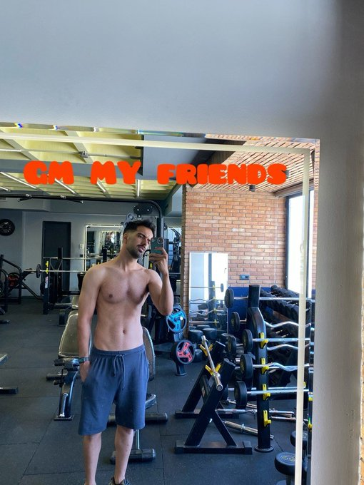 A shirtless man takes a mirror selfie in a gym beneath the text “GM MY FRIENDS.” The post contrasts the community’s usual focus on extracting value from Web3 with the genuine support and opportunities offered by @IronAllies_.
