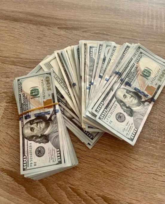 A fan of $100 bills is stacked on a wooden surface, with the caption highlighting the hustle and dedication required to earn such a substantial amount of money.