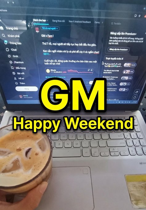 A laptop displaying a Vietnamese-language music site is paired with a glass of iced coffee, overlaid with yellow text reading 'GM Happy Weekend'.