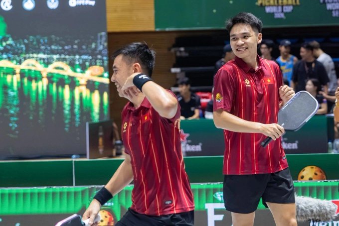 Two male athletes in red Vietnamese team uniforms celebrating with paddles on a pickleball court during a World Cup event.
