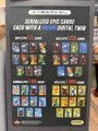 The image shows a promotional display for VeVe's newest digital collectibles, with signage reading "NEW ARRIVALS" and "AVAILABLE ON VEVE!" above rows of colorful digital trading card packs. The display corresponds to the post's announcement about trading cards launching on the VeVe digital collectibles platform, showcasing the new vertical of NFT-style cards now available for purchase.