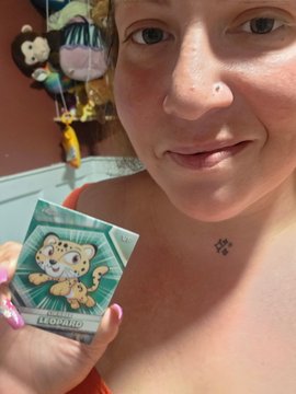 A woman holds up a small card or sticker with an illustration of a leopard labeled 'LEOPARD'.